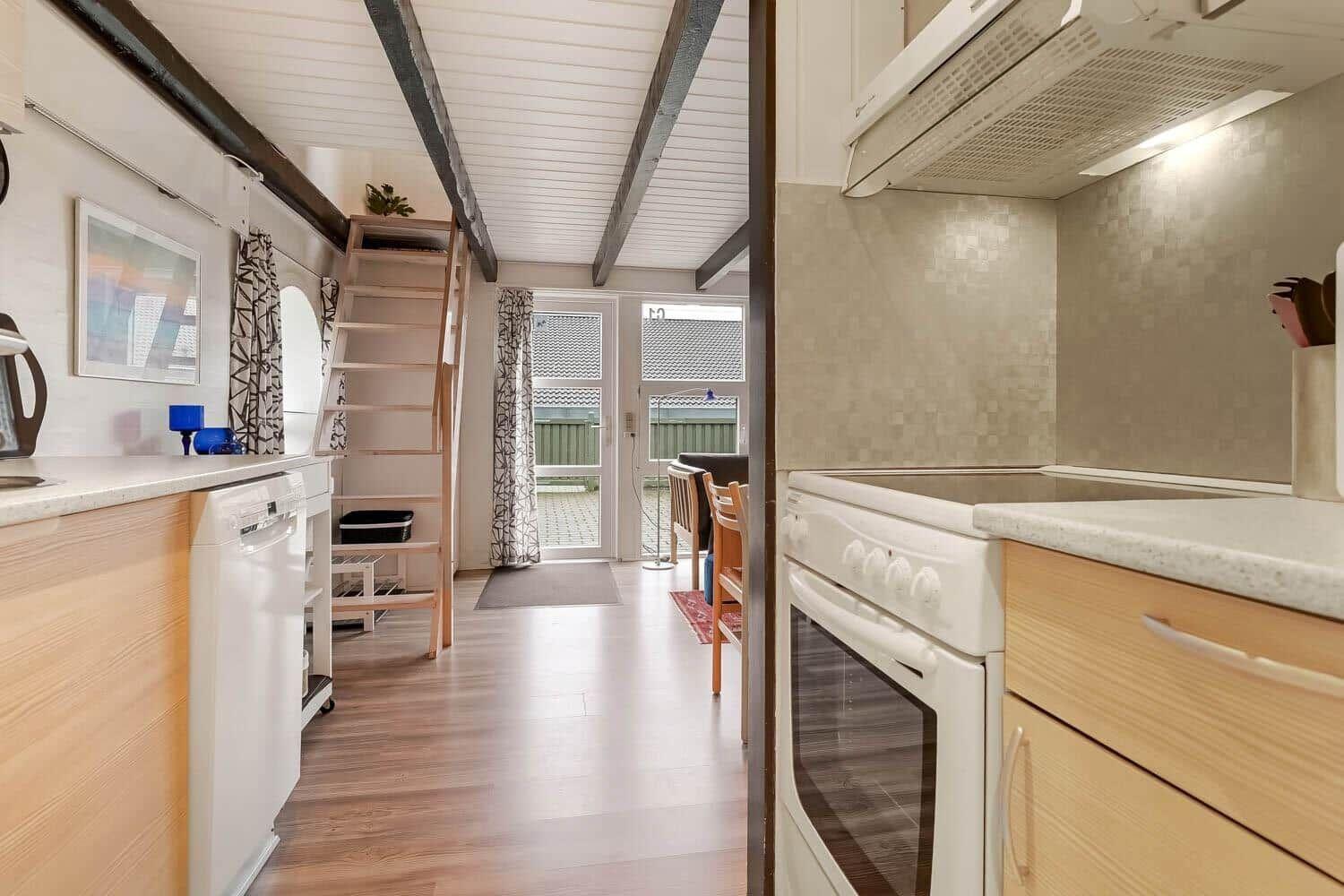 Küche mit Spüle, Herd und Kühlschrank. Treppenhaus führt zu oberem Stockwerk.