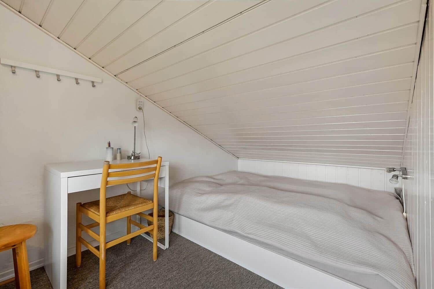 Ein Schlafzimmer mit Doppelbett, Schreibtisch und Stuhl unter schrägem Dach.