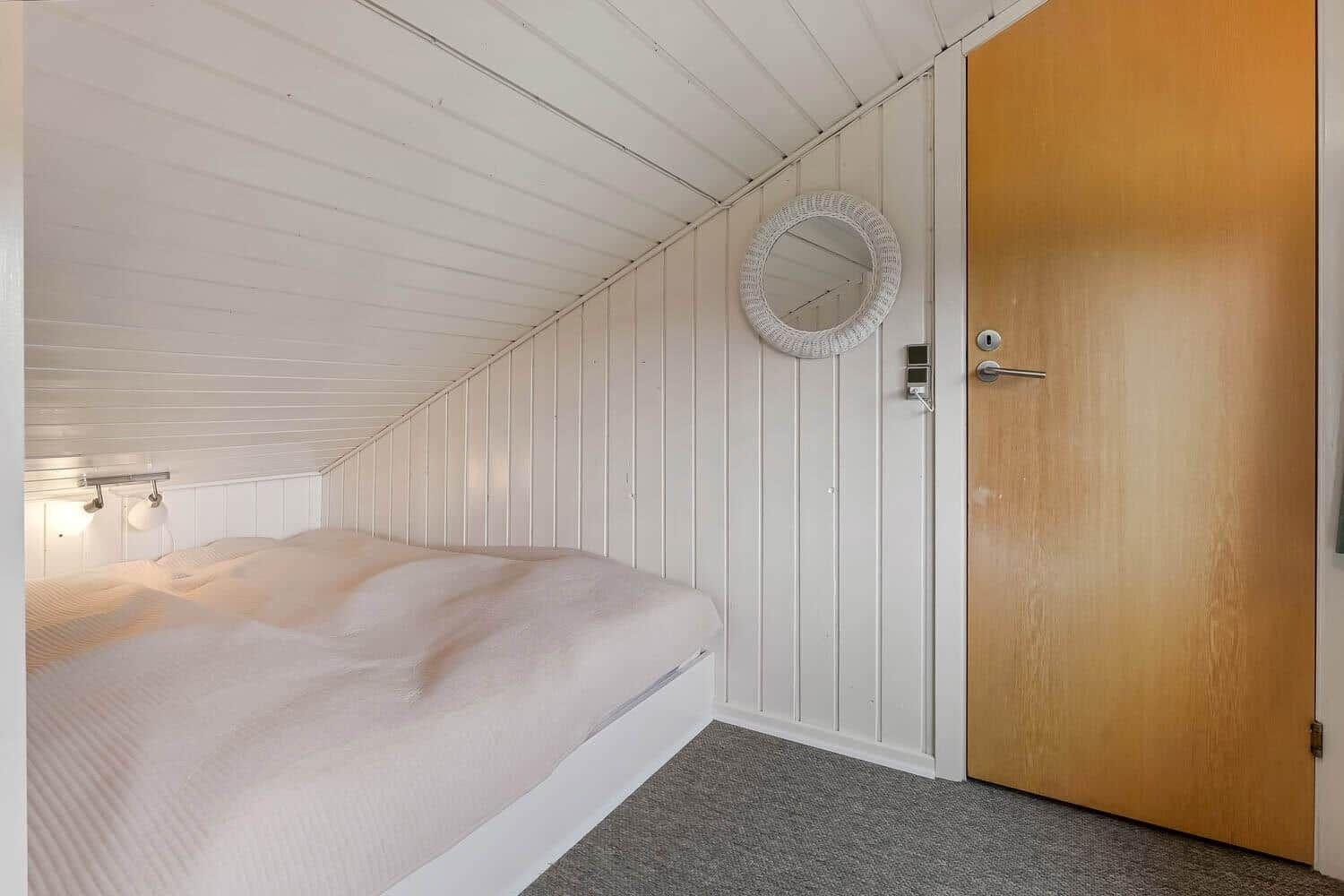 Schlafzimmer mit Bett, Spiegel und Tür