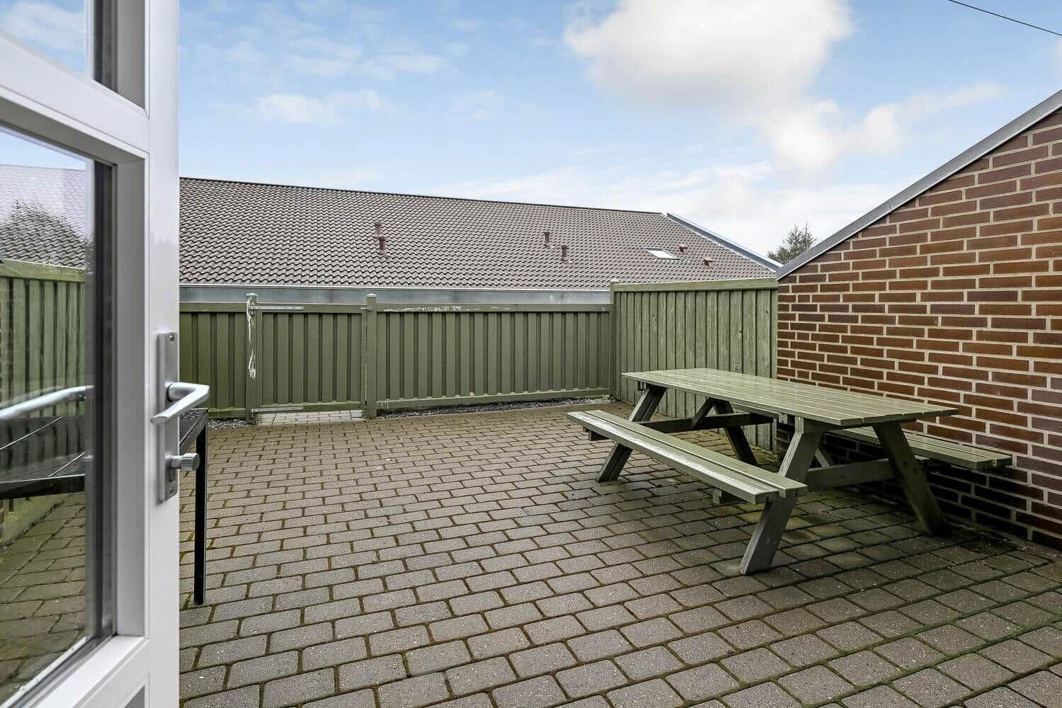 Terrasse mit Picknicktisch, umgeben von Holz- und Ziegelmauer.