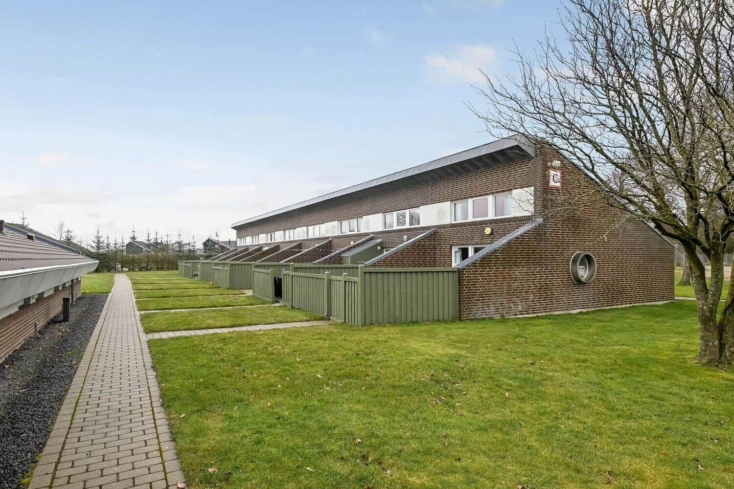 Einfamilienhaus mit Garten und Terrasse. Holztor und Zufahrtsweg sichtbar.