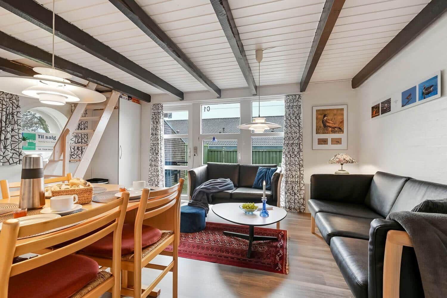 Wohn- und Essbereich mit Sofa, Tisch und Holzdecke.