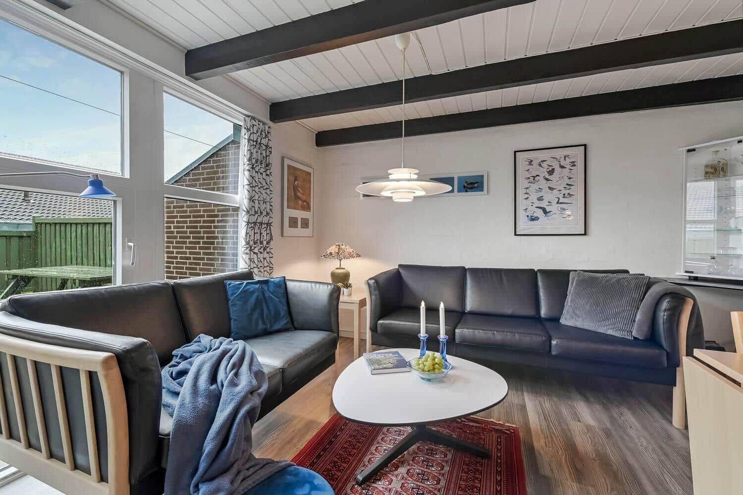 Wohnzimmer mit zwei Sofas, Tisch und Fenstern.
