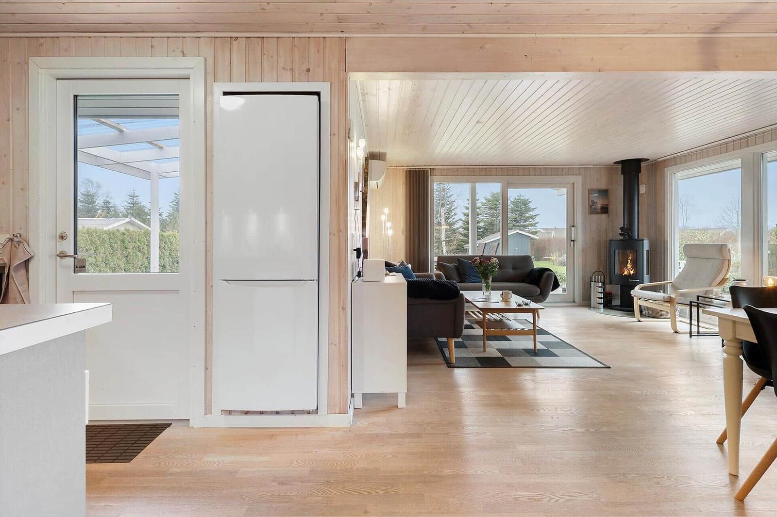 Apartment with kitchen, living room, and wood stove. Wooden floor and large windows.