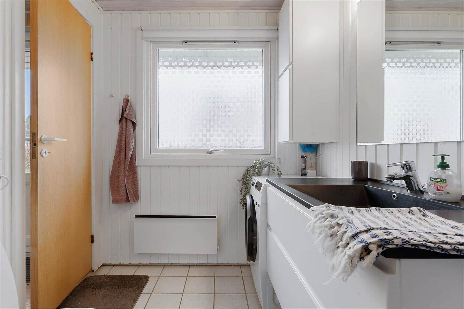 Utility room with washing machine, sink, and window