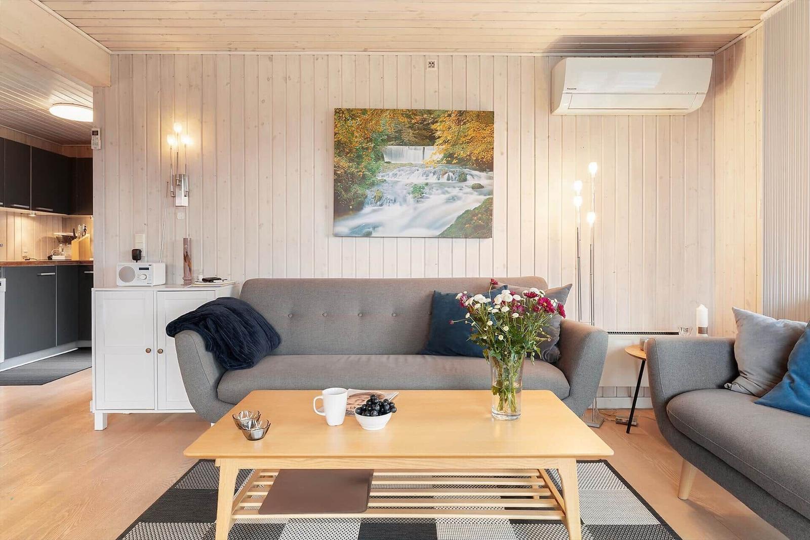 Living room with sofa, coffee table, and wall art. Kitchen area in background.