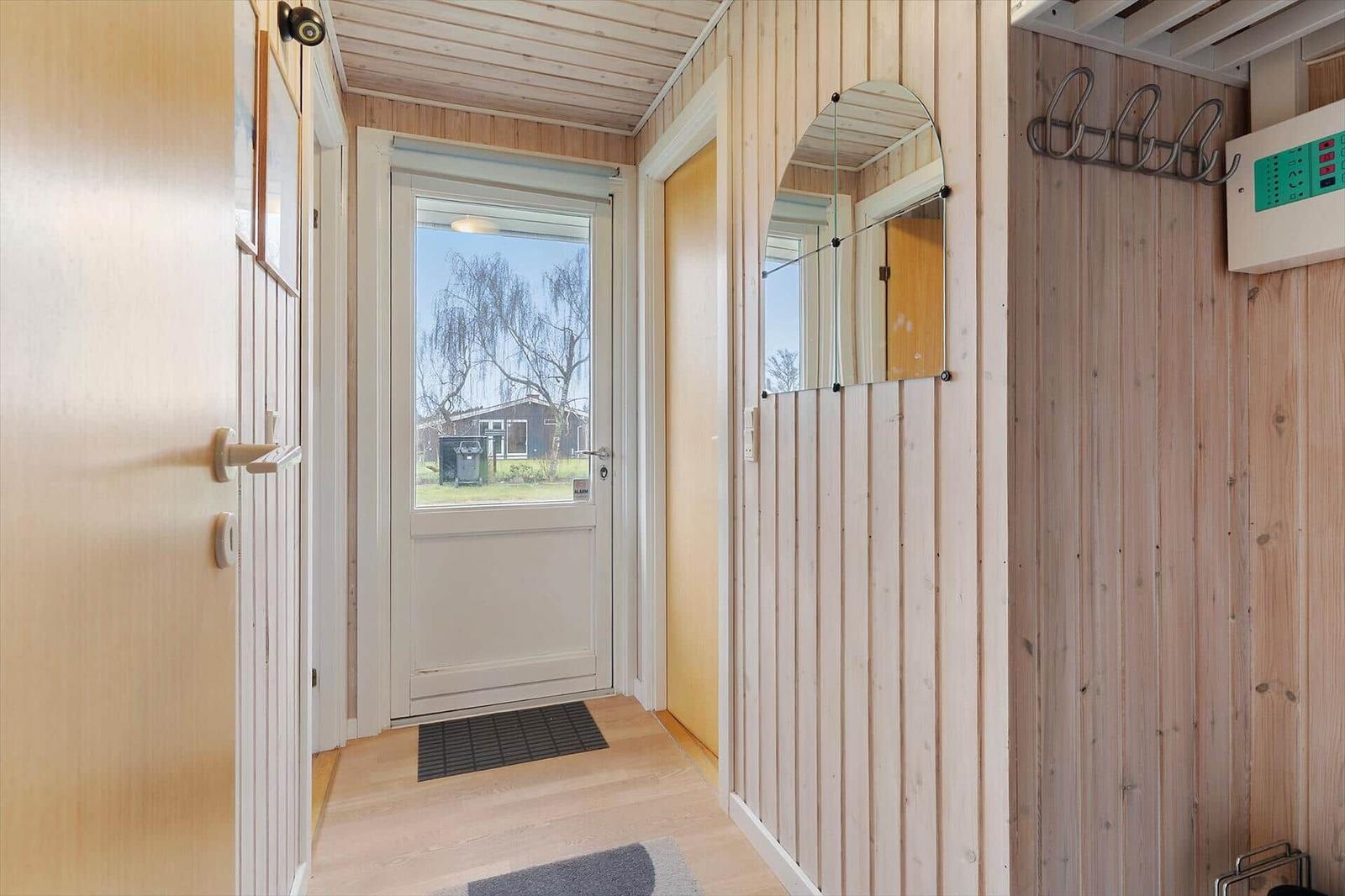 Entrance area with wooden wall, mirror, and door to outdoor area.