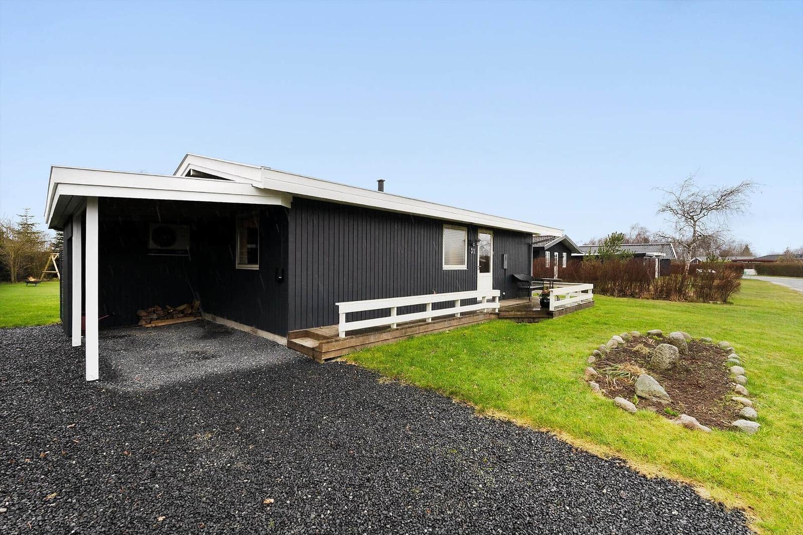 A black house with a white porch and garden.