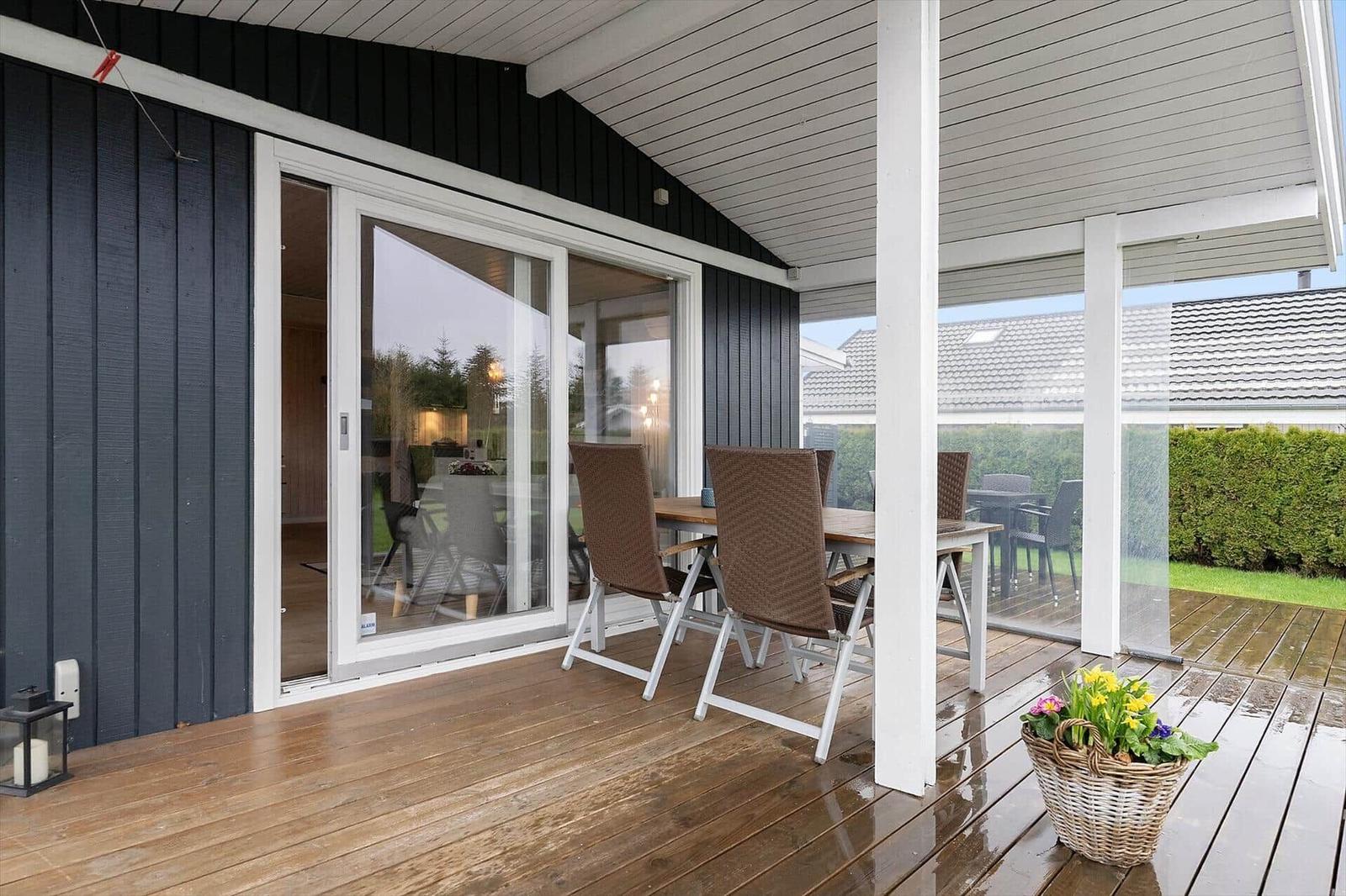 Deck with table, chairs, and flower basket. Sliding glass door leads into the house.