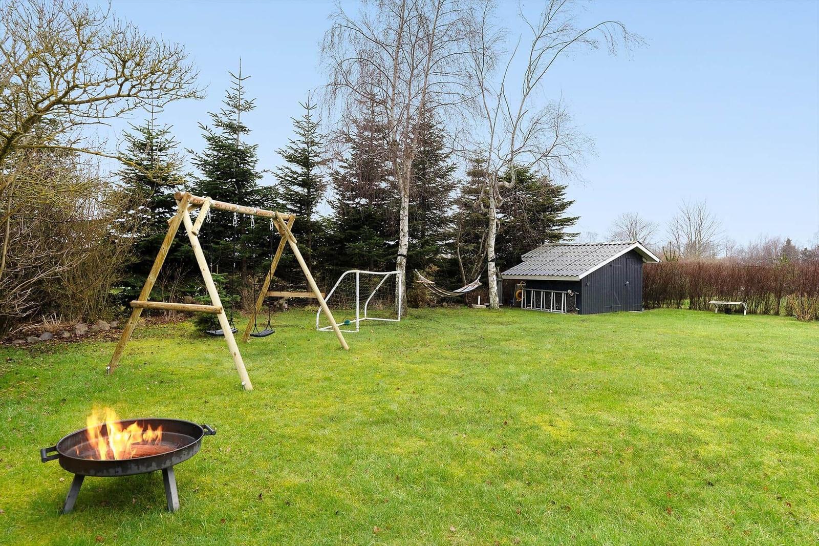 Backyard with fire pit, swing, soccer goal, and small shed.