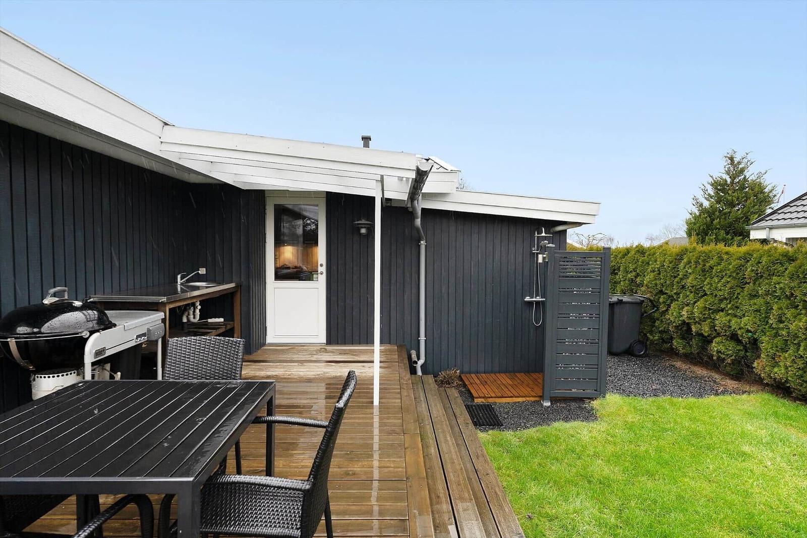 Outdoor area with grill, table, seating, and shower