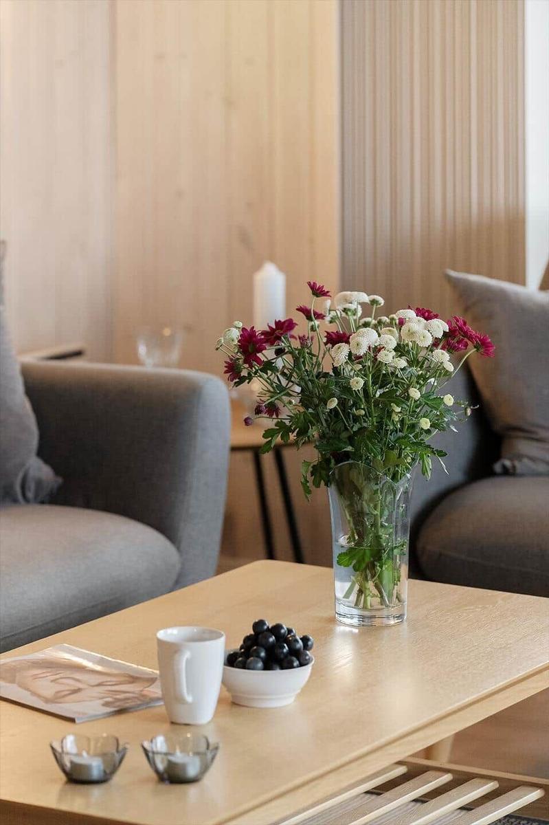 A table with flowers, coffee cup, and grapes in the living area.