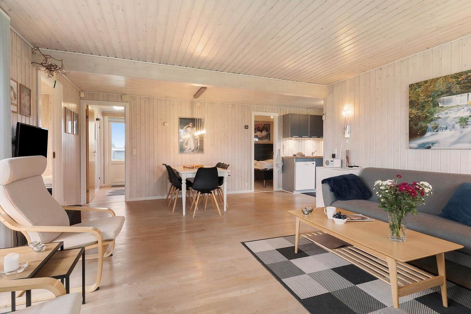 Living room with dining area and kitchen. Wooden ceiling, sofa, coffee table, and artwork.