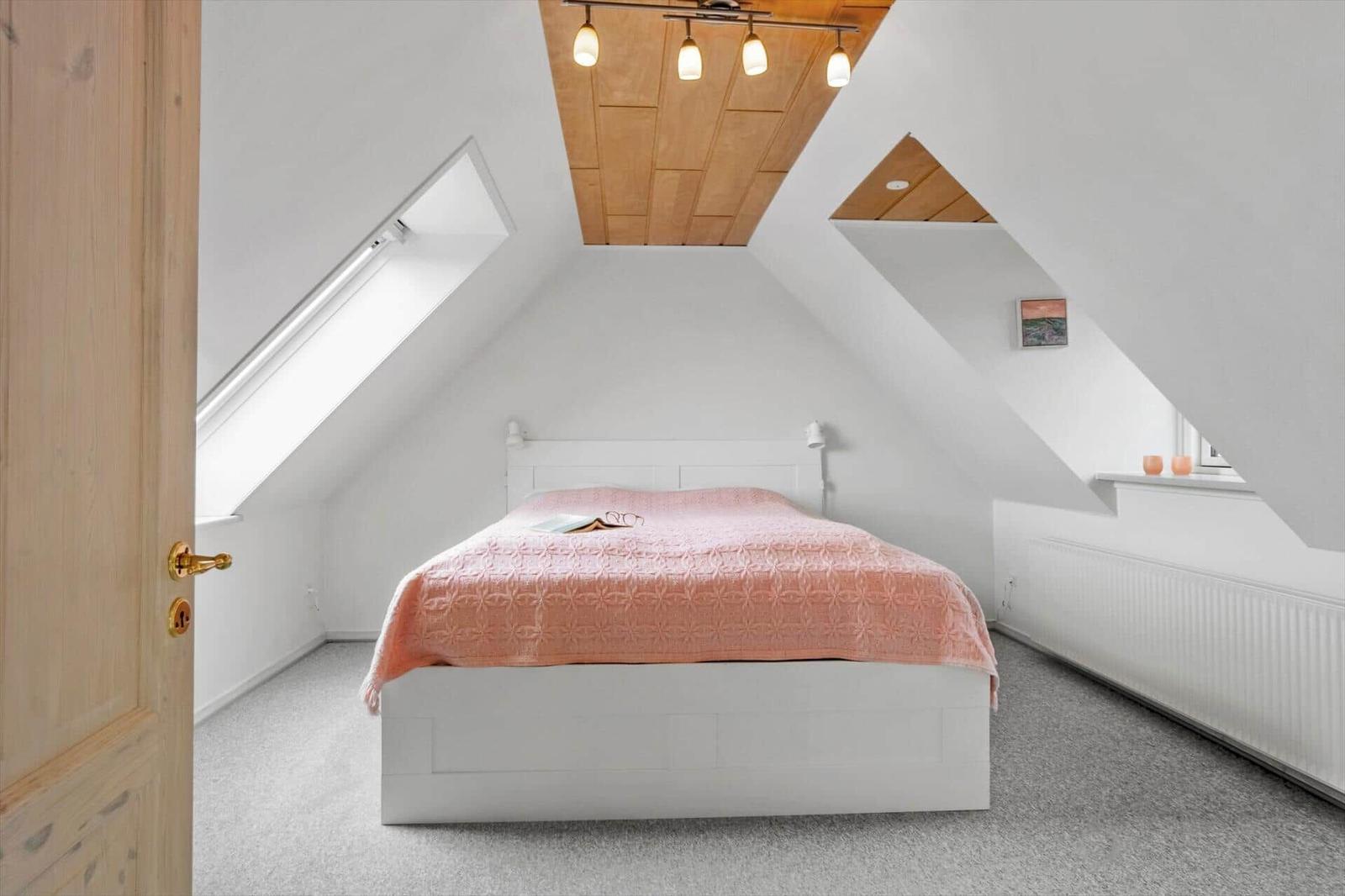 Schlafzimmer mit Dachschrägen, Bett und Fenster