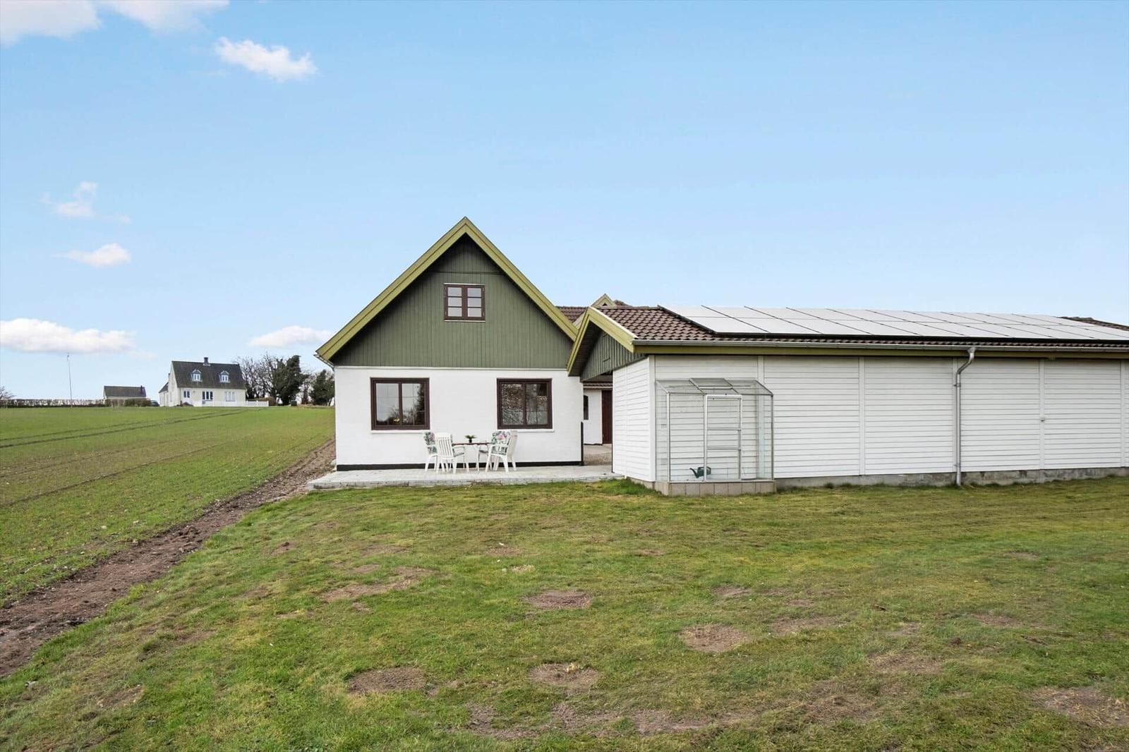 Haus mit grünem Dach und weißem Anbau, Garten und Tisch mit Stühlen