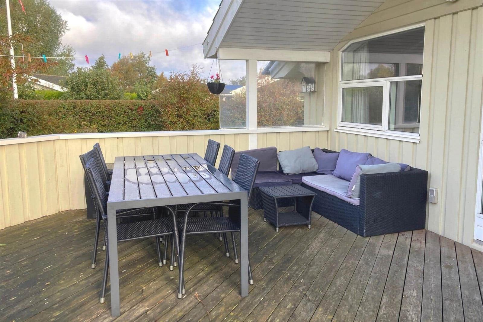 Deck with table, chairs, and sofa under roof.