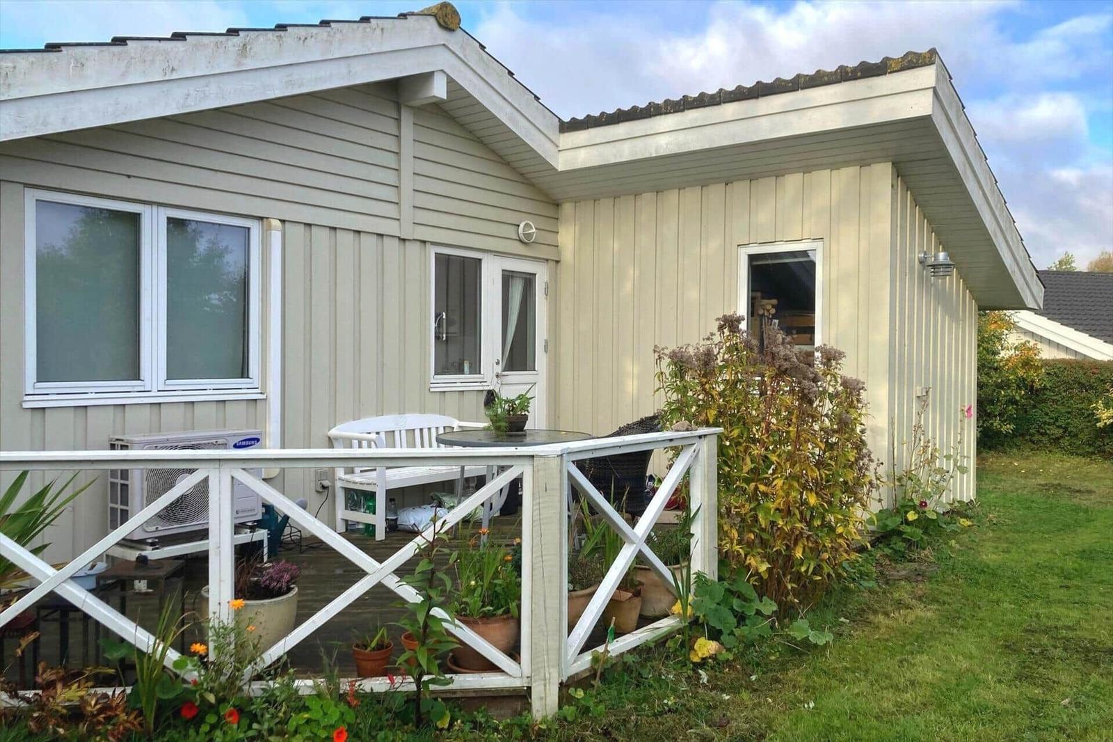 House with terrace, garden and plants. White wooden veranda with table and chairs.