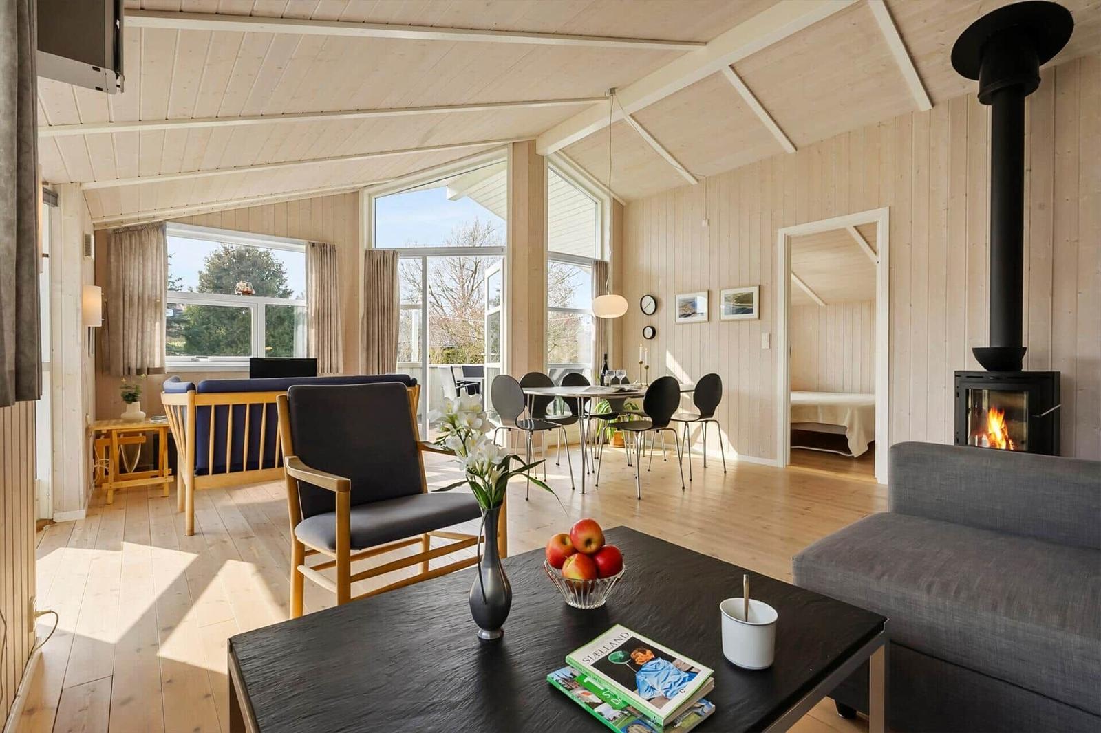 Living and dining area with fireplace, large windows, and wooden elements.