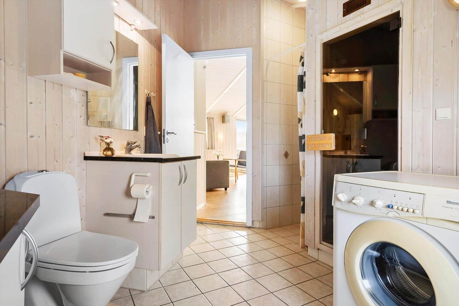 Bathroom with toilet, washing machine, and sauna entrance.