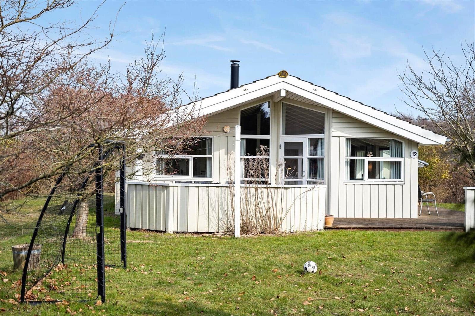 House with wooden porch and garden. Soccer ball lies on the lawn.