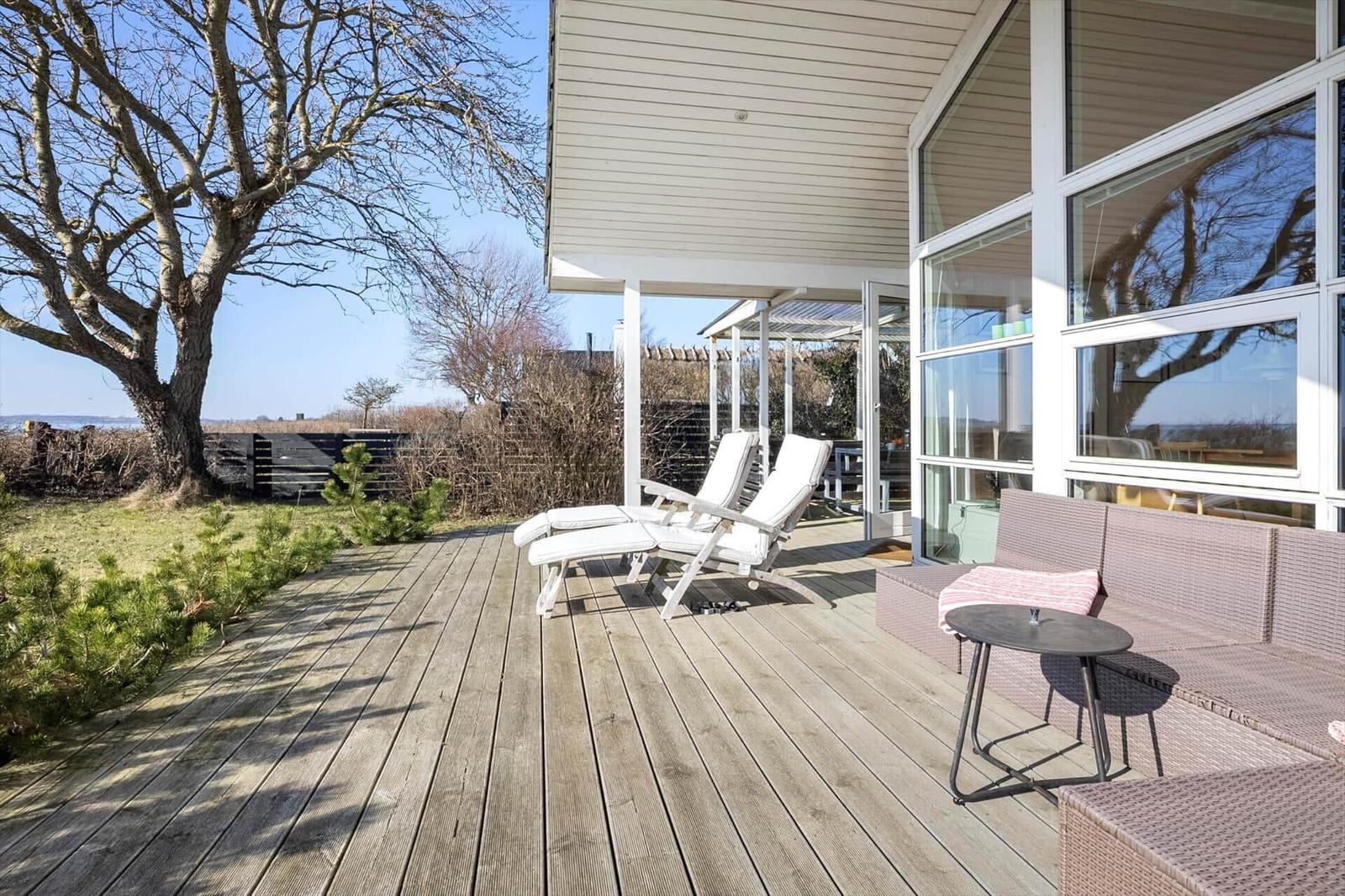 Deck with lounge chairs and seating group, view of tree and landscape.