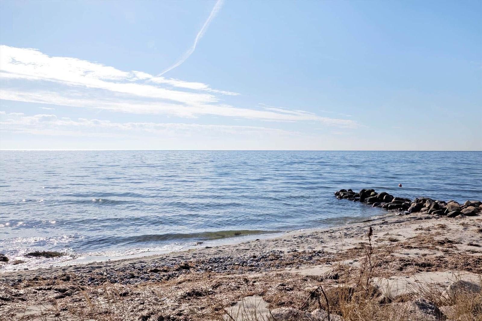 Beach with stones and calm sea under blue sky.