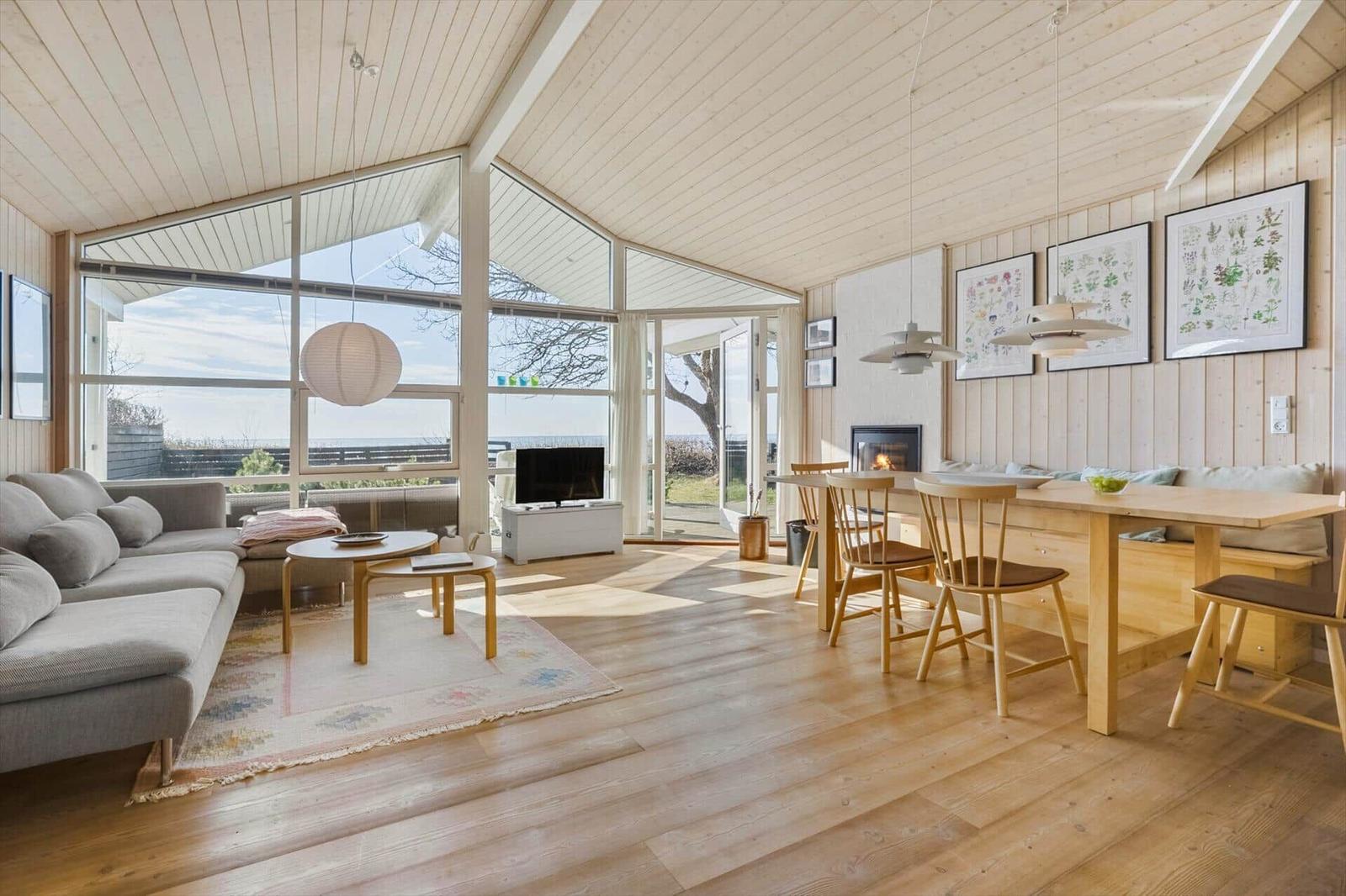 Living and dining area with wooden ceiling, large windows, and dining table with chairs.