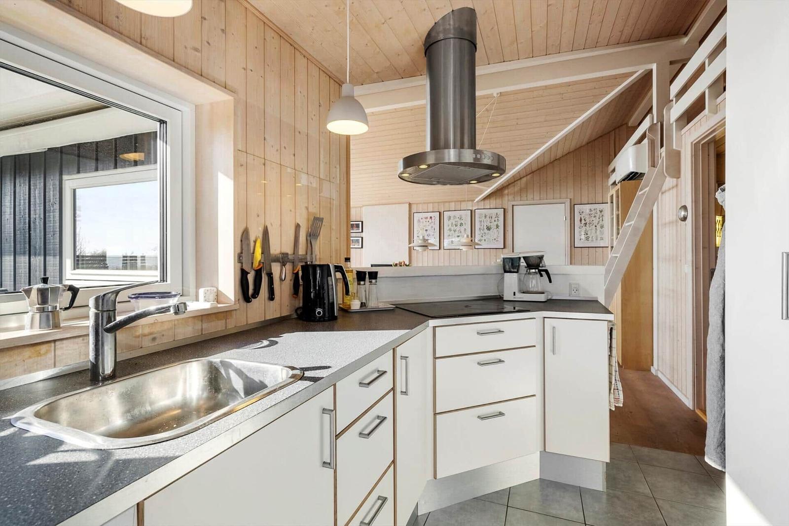 Kitchen with wooden walls, sink, stove, and range hood.