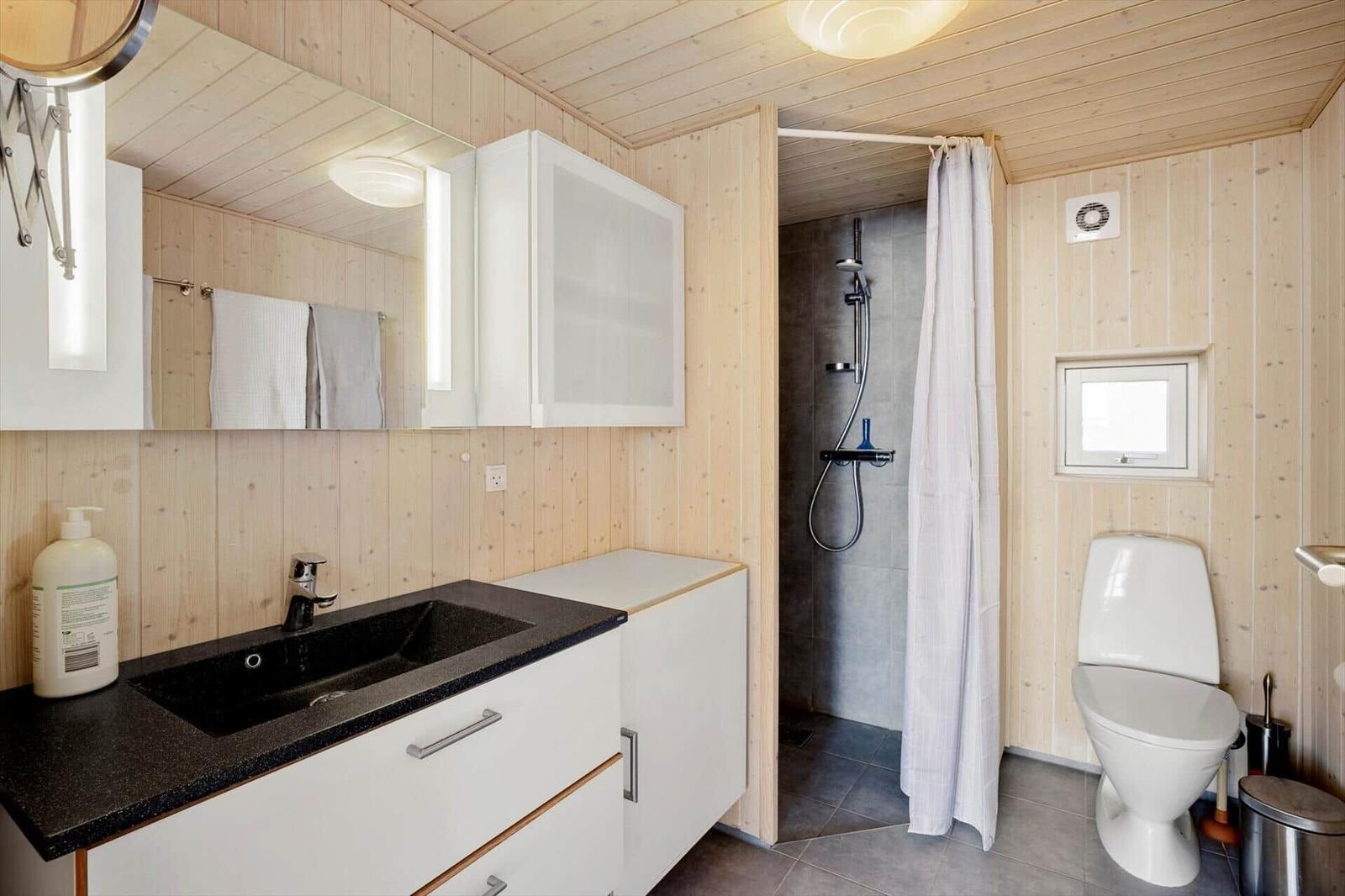 Bathroom with shower, toilet, and sink with mirror.
