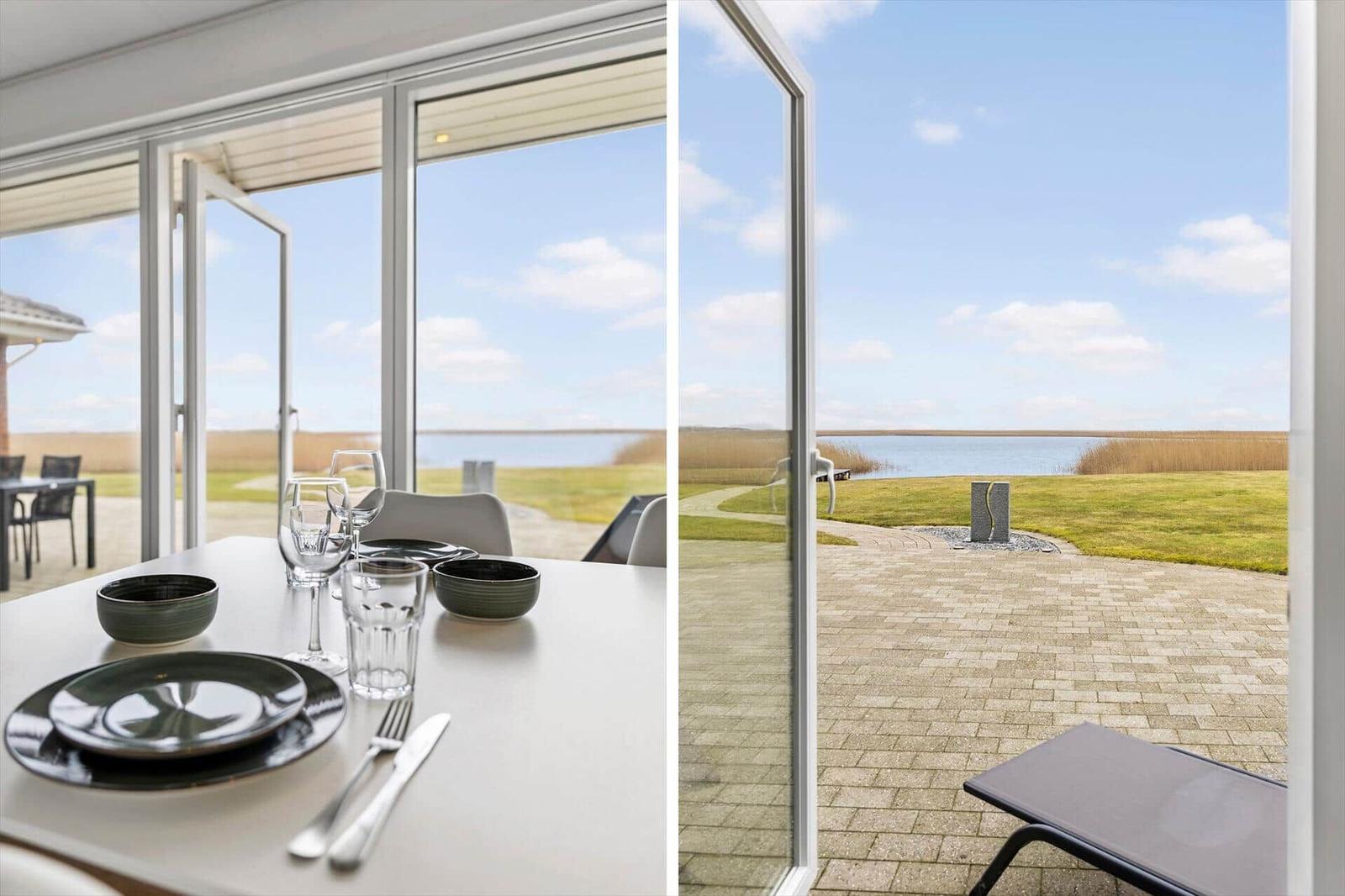 Esszimmer mit Blick auf einen See und einen gepflasterten Außenbereich.