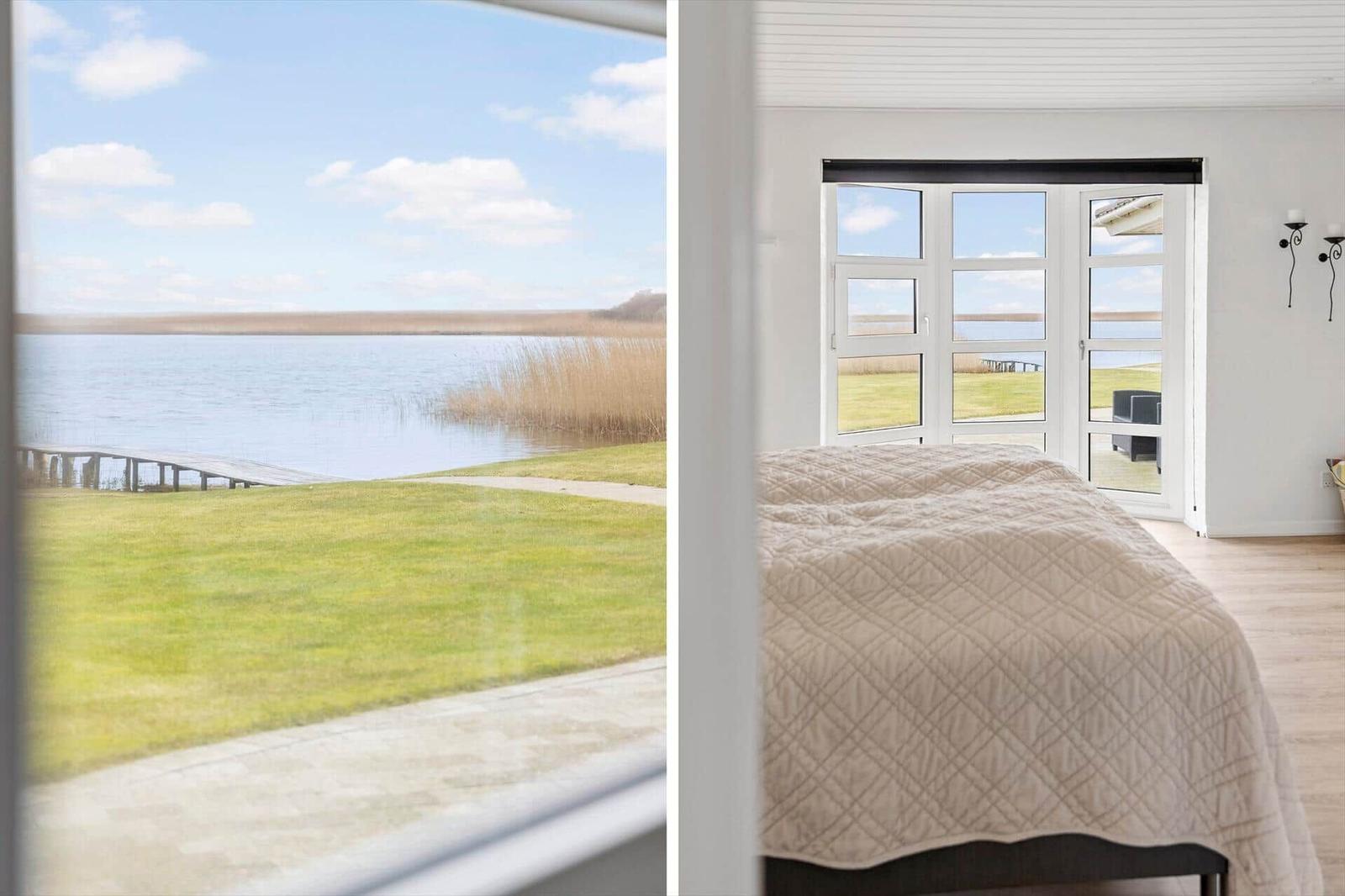 Schlafzimmer mit Blick auf See und Grasfläche. Fenster und Tür führen nach draußen.