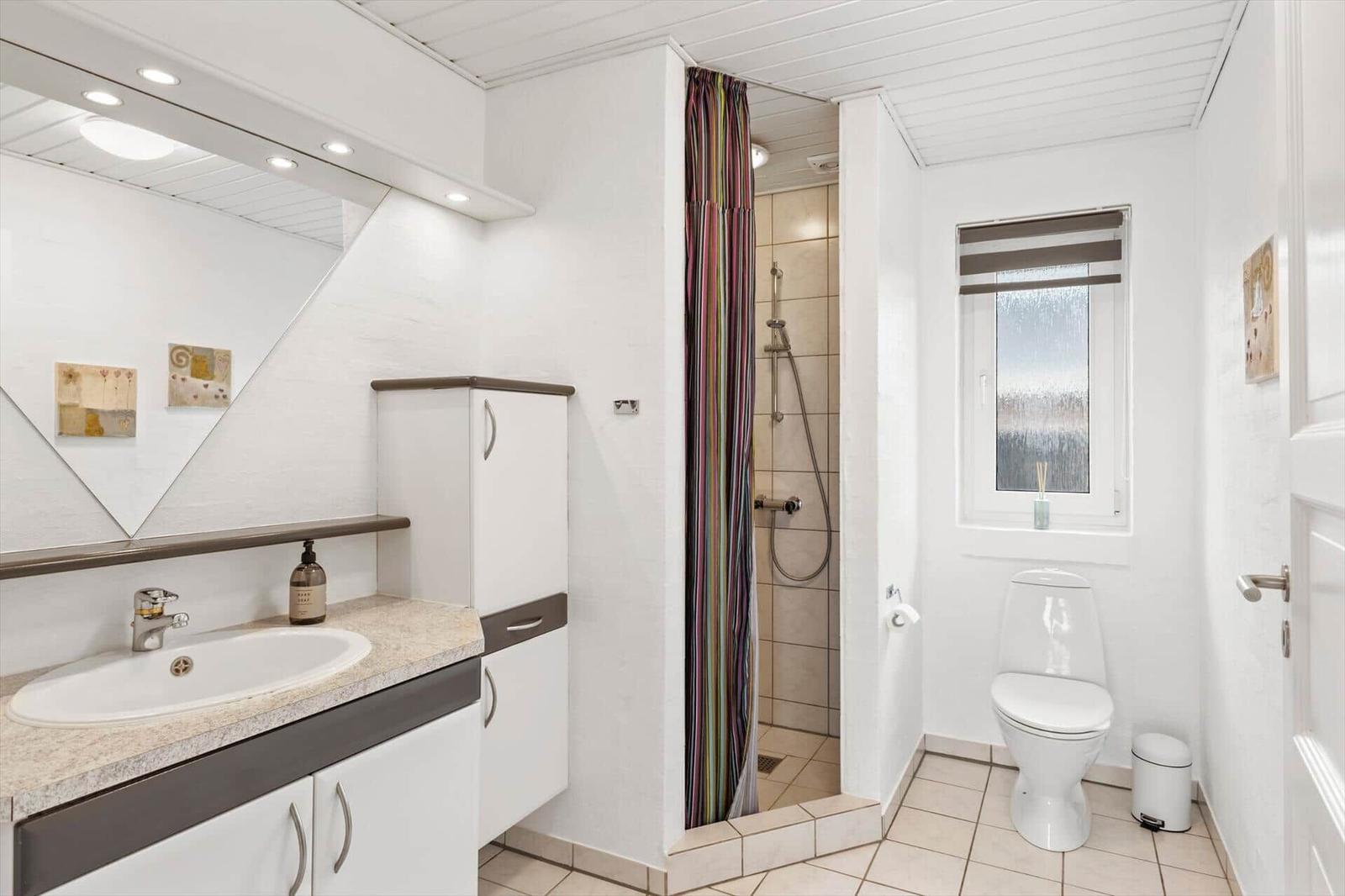 Badezimmer mit Dusche, Toilette und Waschbecken mit Spiegel.