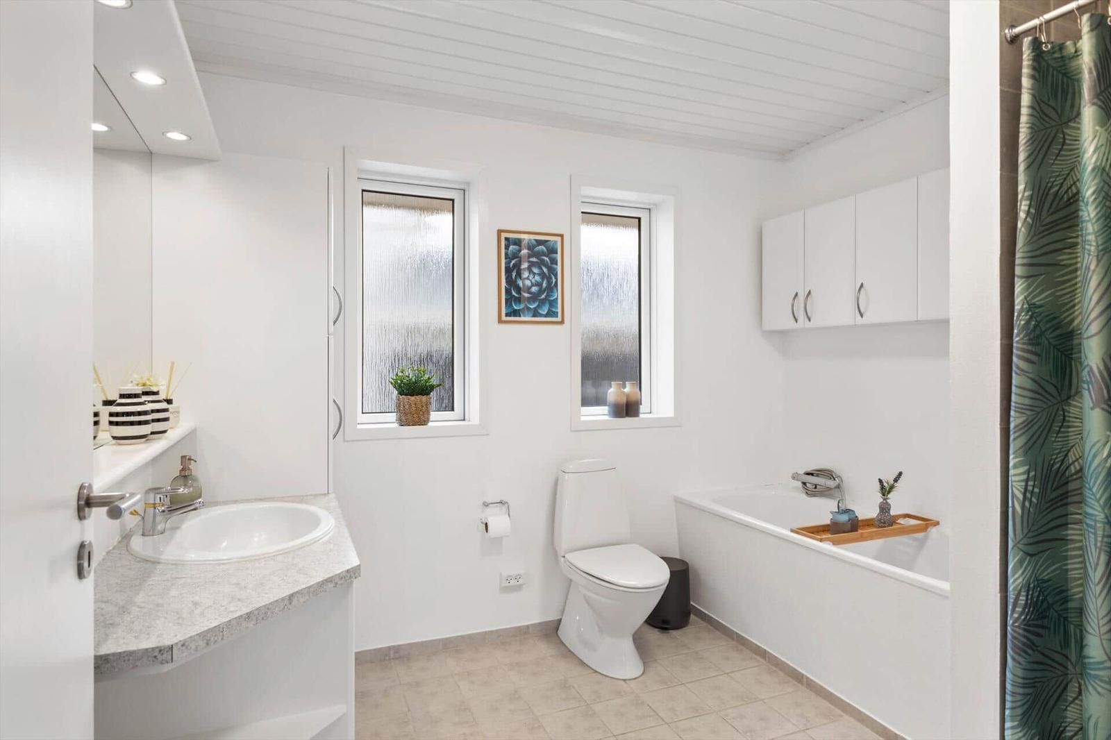 Badezimmer mit Badewanne, Toilette und Waschbecken mit Spiegel.