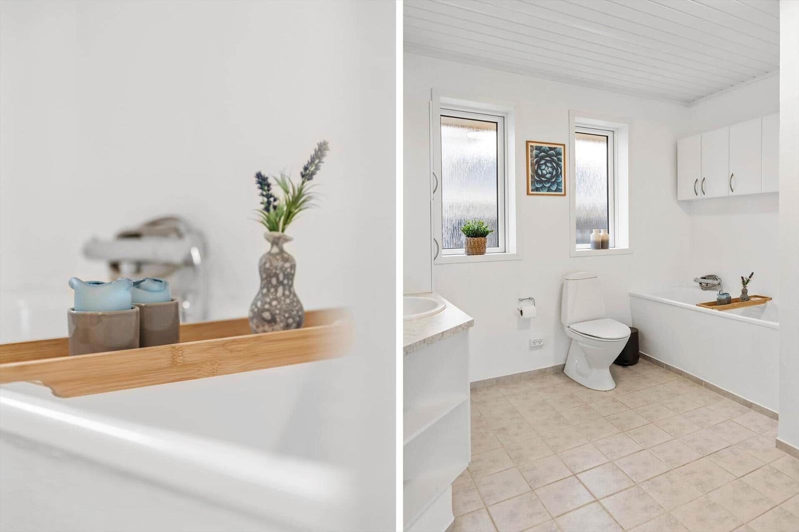 Badezimmer mit Badewanne, Toilette und Fenstern mit Pflanzen.