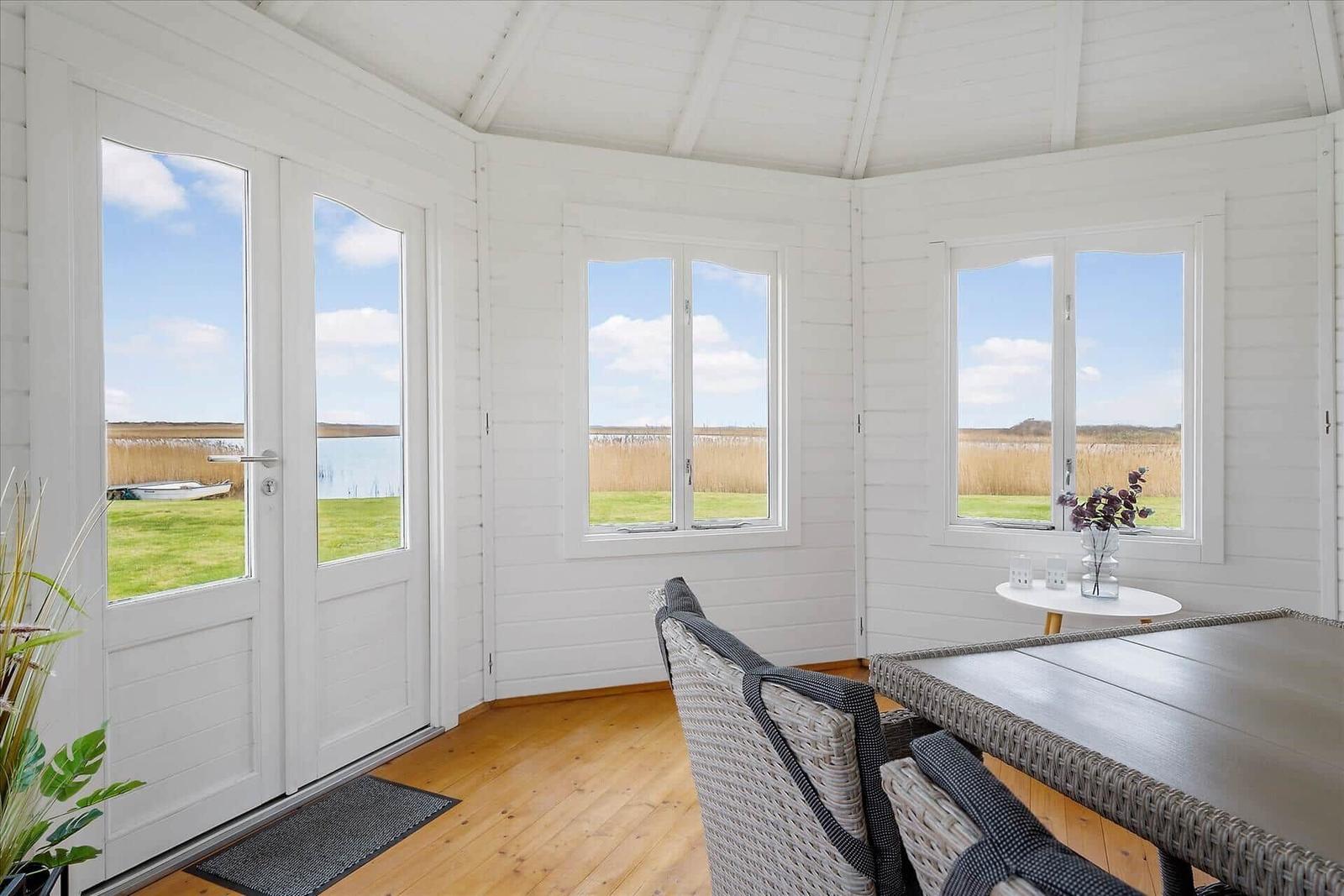 Wohnraum mit Blick auf Wasser und Grasland durch große Fenster und Tür.