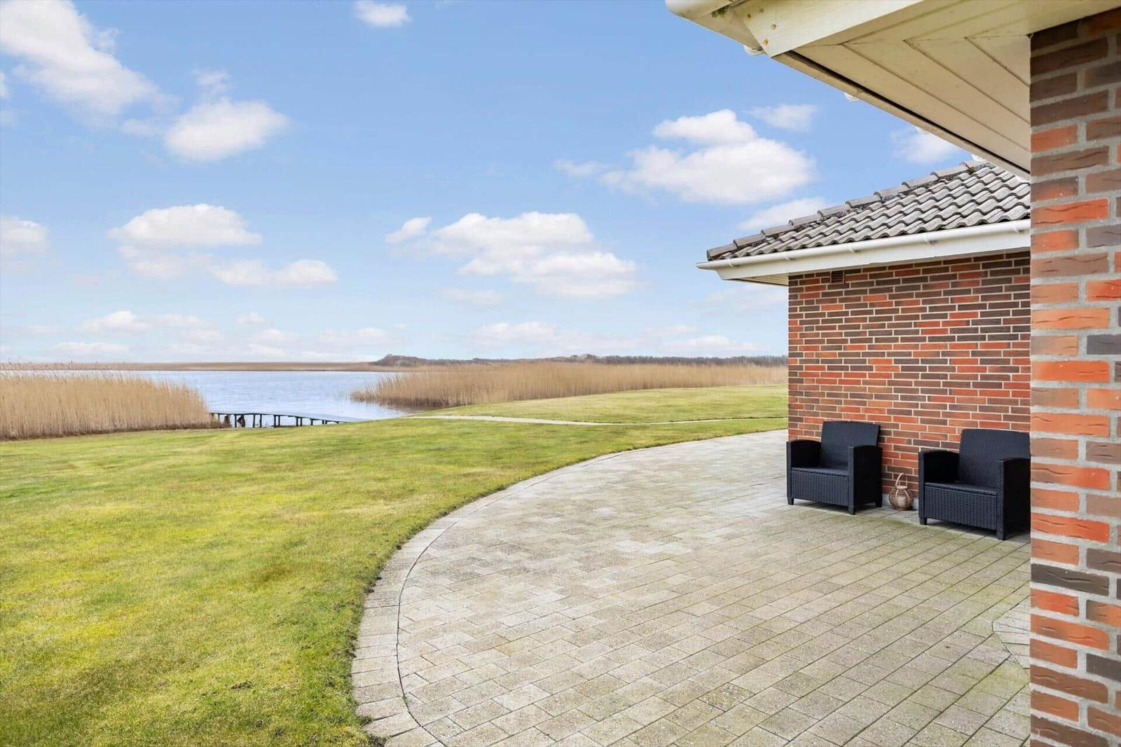 Terrasse mit zwei Sesseln neben einem Haus mit Blick auf einen See.