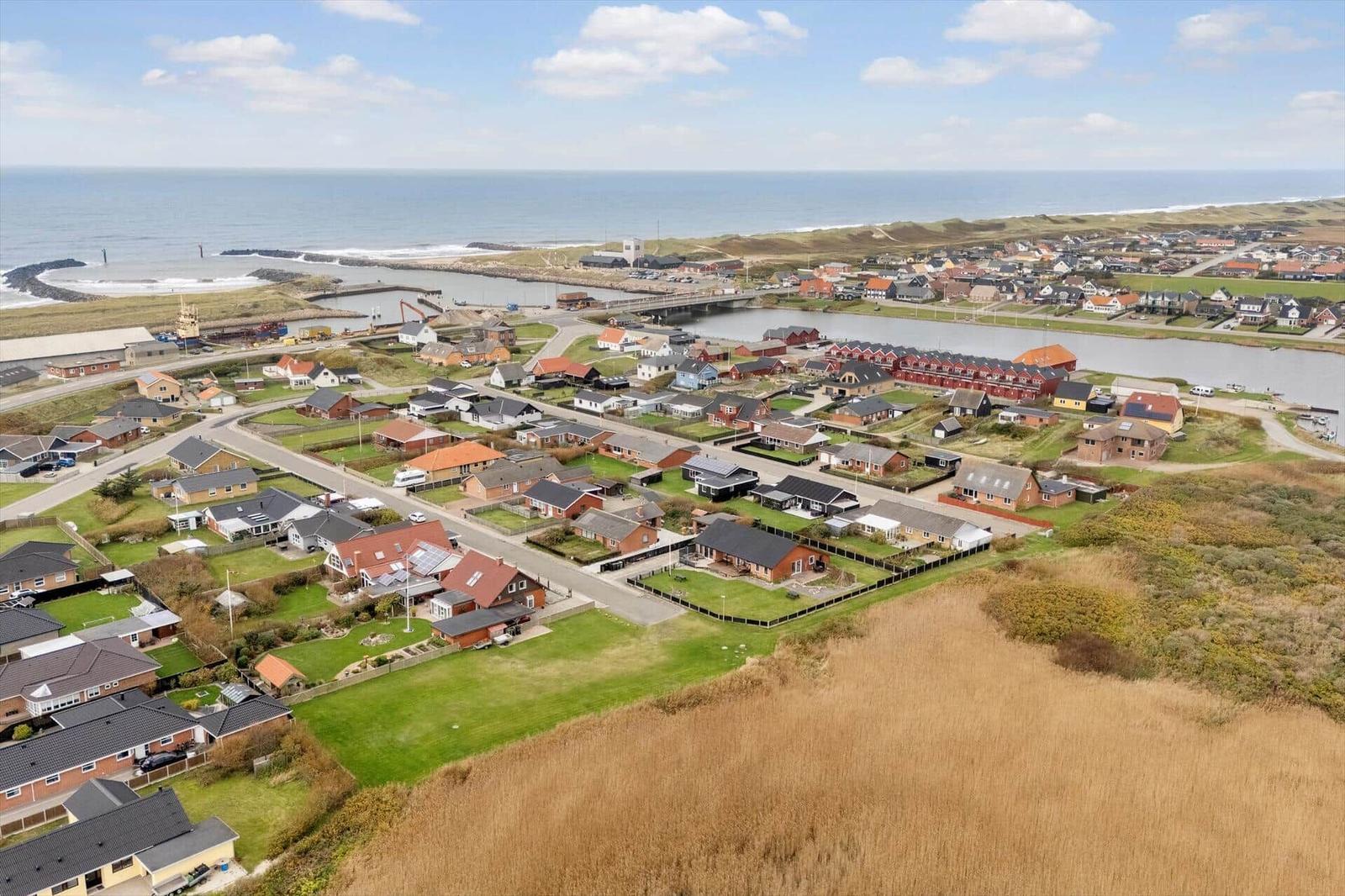 Aerielansicht eines Küstendorfes mit Häusern, Kanal und Meer.