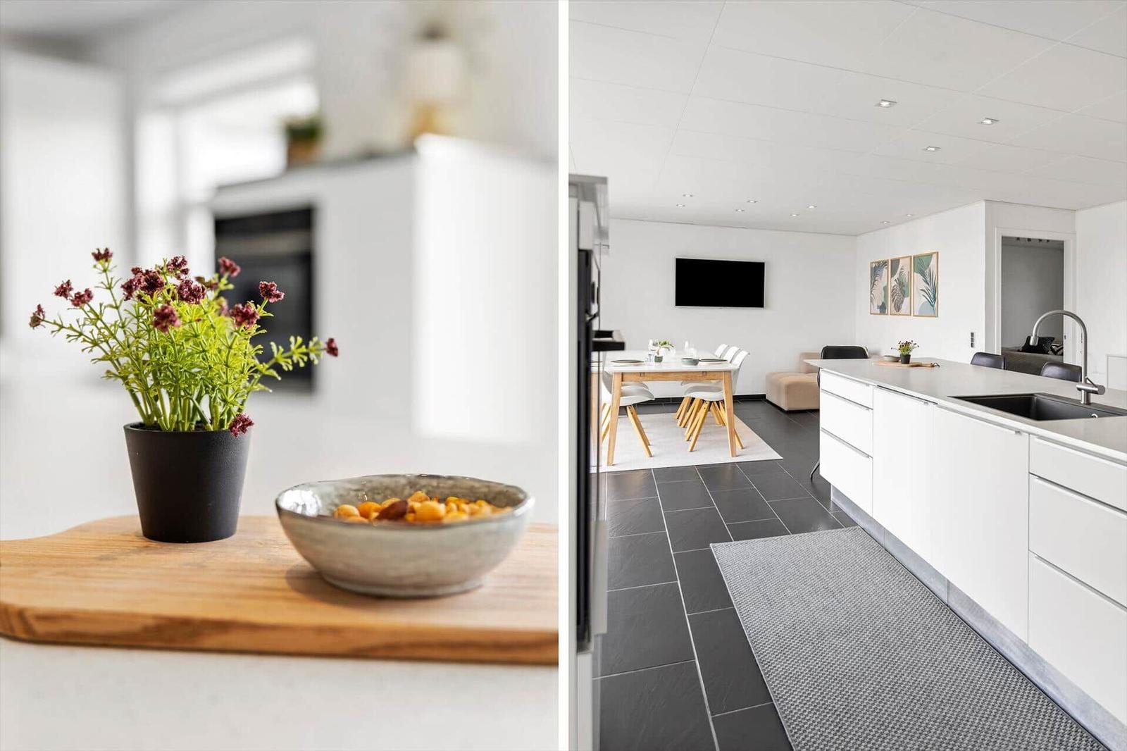 Küche mit Arbeitsfläche, Pflanze und Schale. Wohnbereich mit Esstisch, Fernseher und Wandbildern.