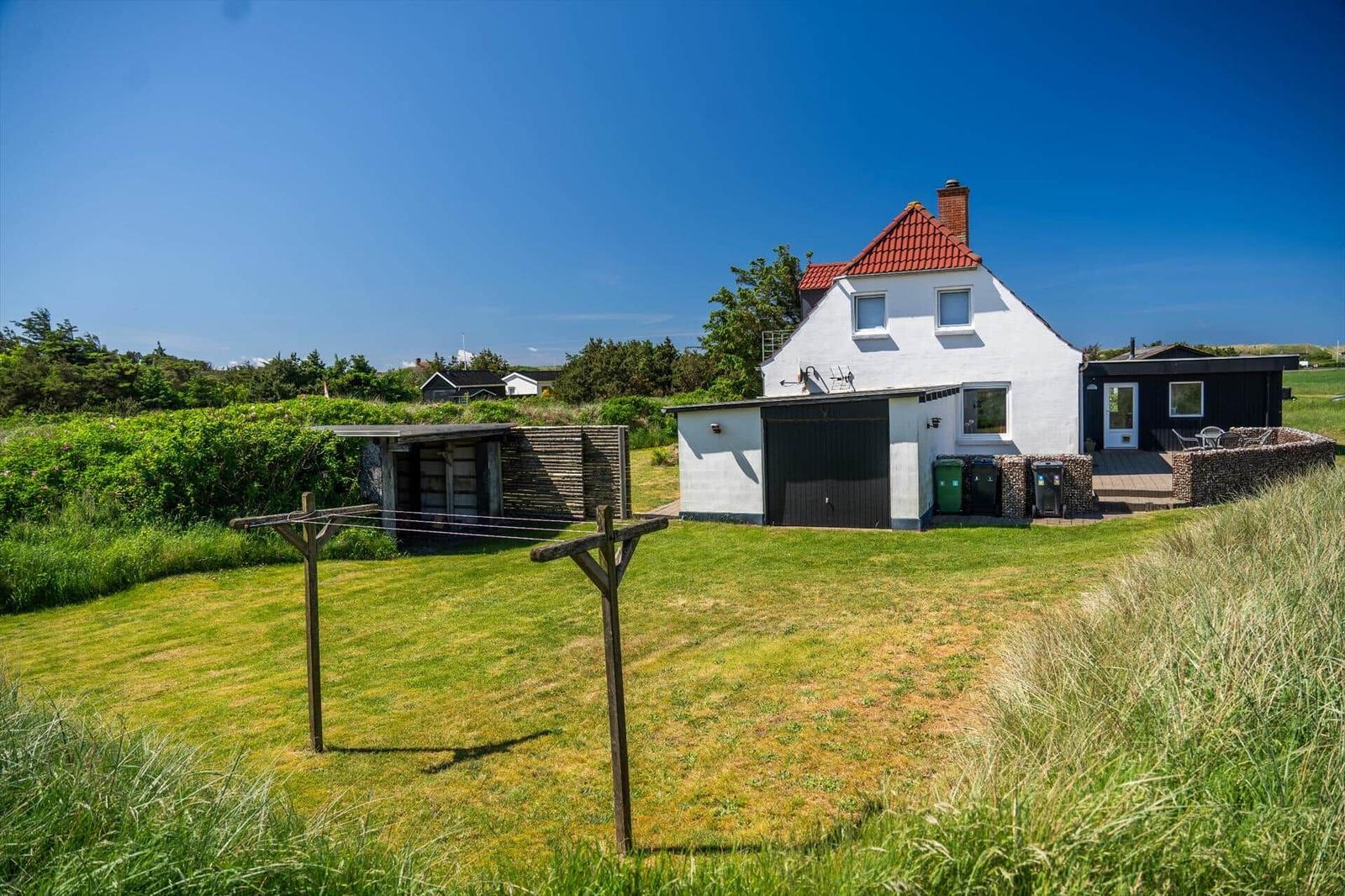 Wohnhaus mit rotem Dach, Garage und Garten mit Wäscheleine.