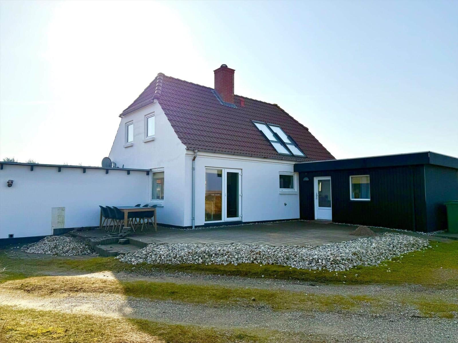 Wohnhaus mit Terrasse, Garten und moderner Anbau. Rotes Dach und weiße Fassade.