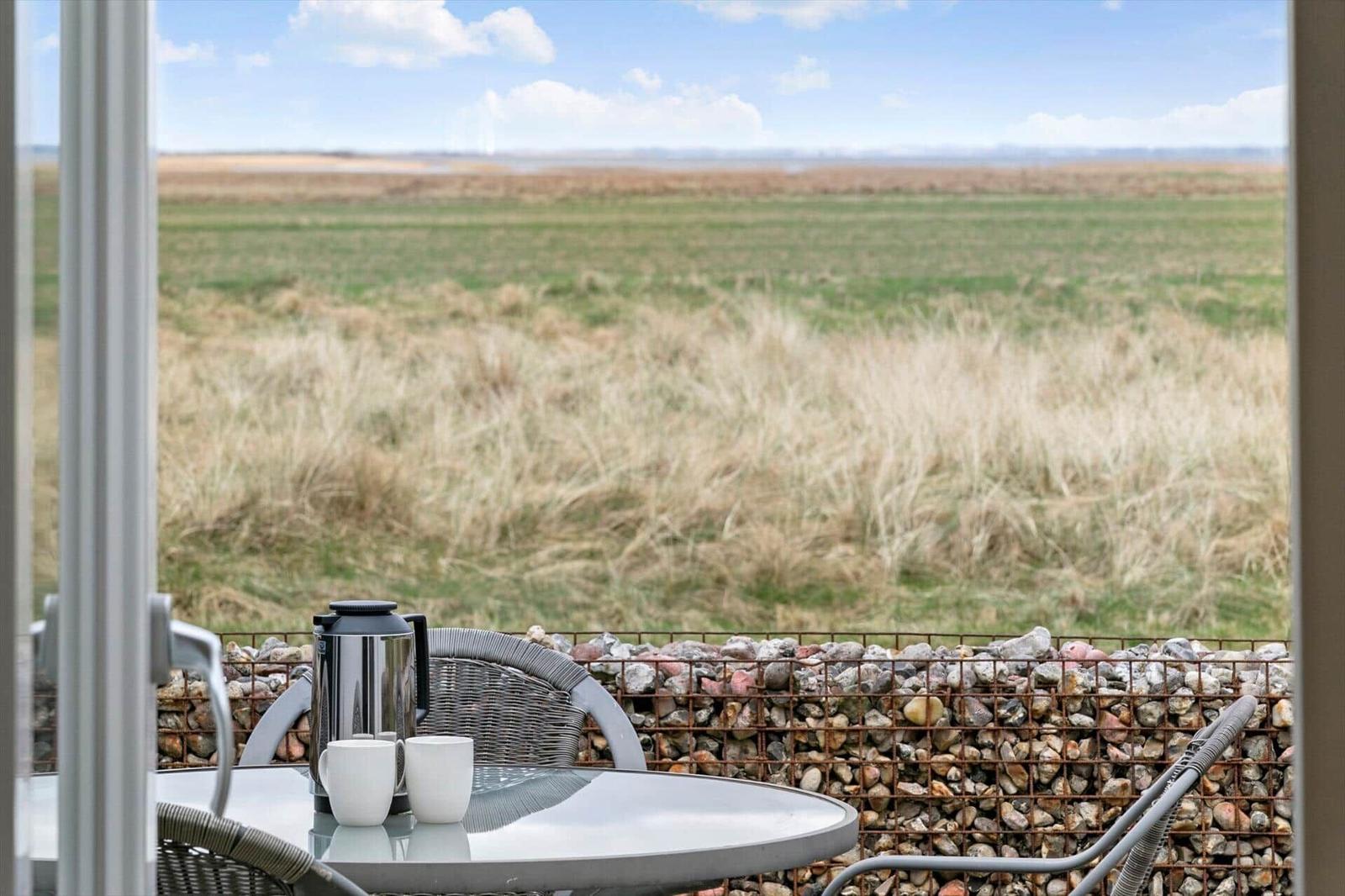 Terrasse mit Tisch, Stühlen und Blick auf Felder.