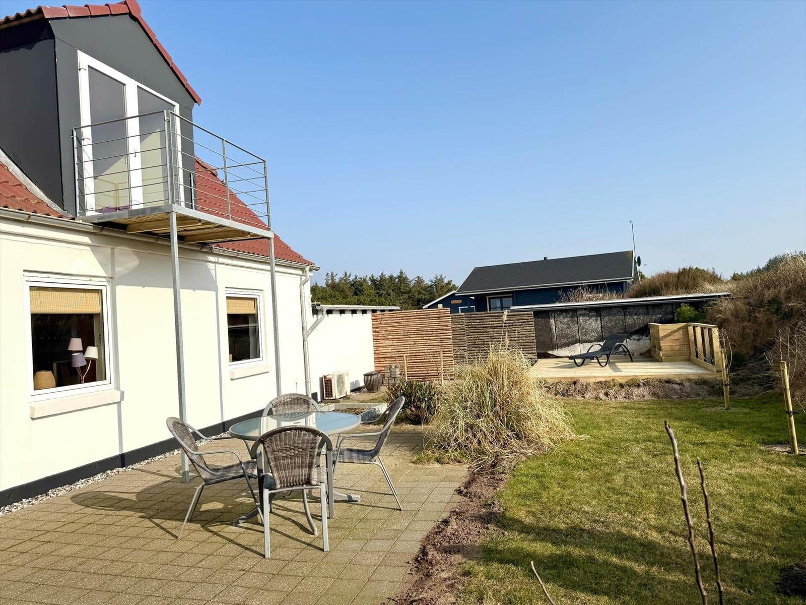 Haus mit Terrasse, Garten und Sonnenliegeplatz. Außenbereich mit Tisch und Stühlen.