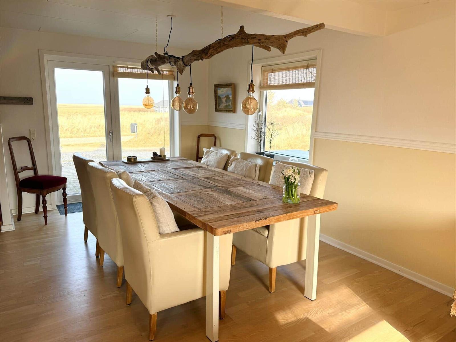 Esszimmer mit Holztisch, cremefarbenen Stühlen und rustikaler Deckenleuchte.