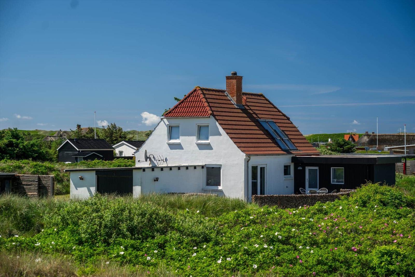 Ein weißes Haus mit rotem Dach und Garten im Vordergrund.