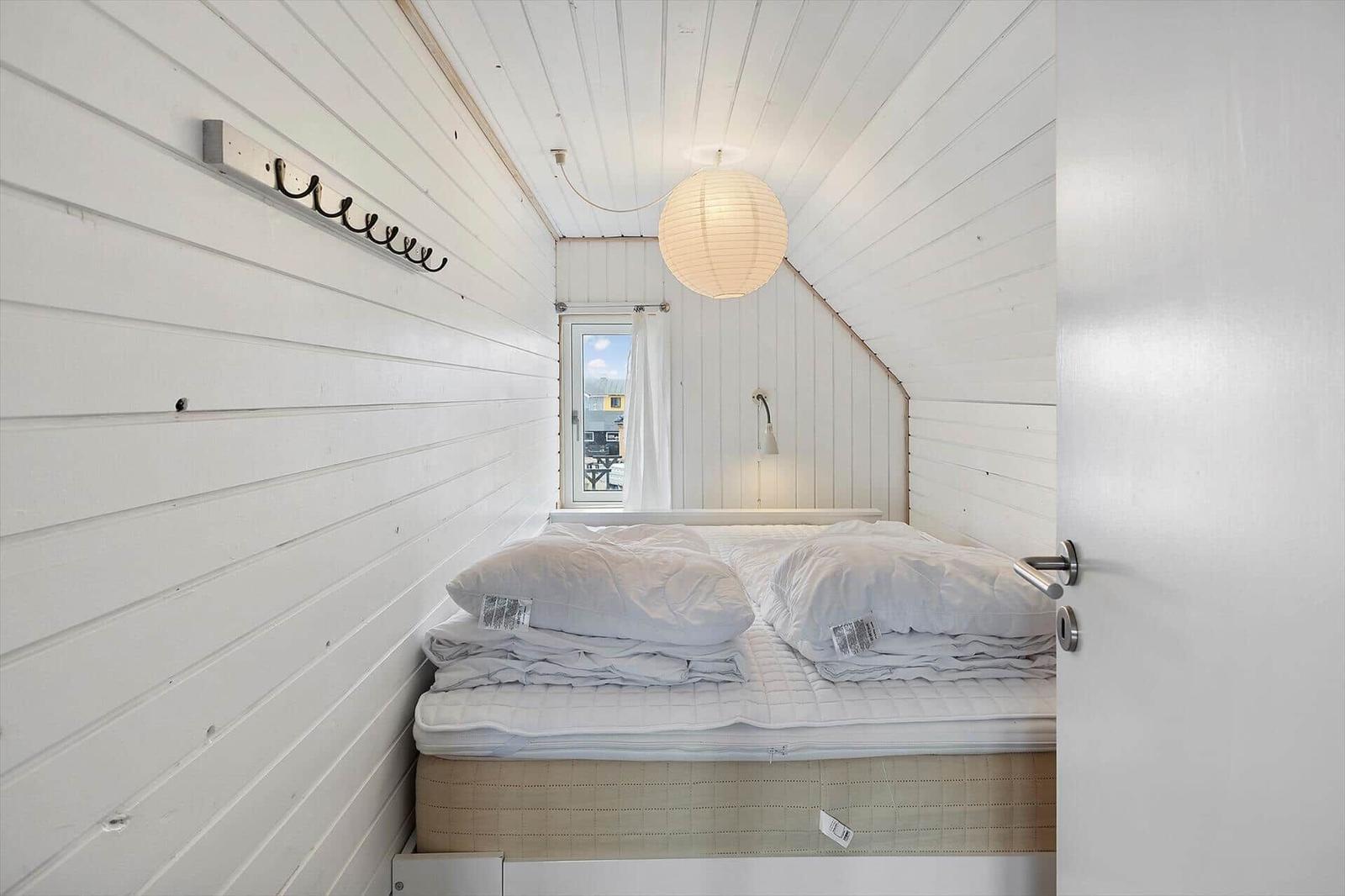 Schlafzimmer mit Bett, Fenster und Deckenleuchte.