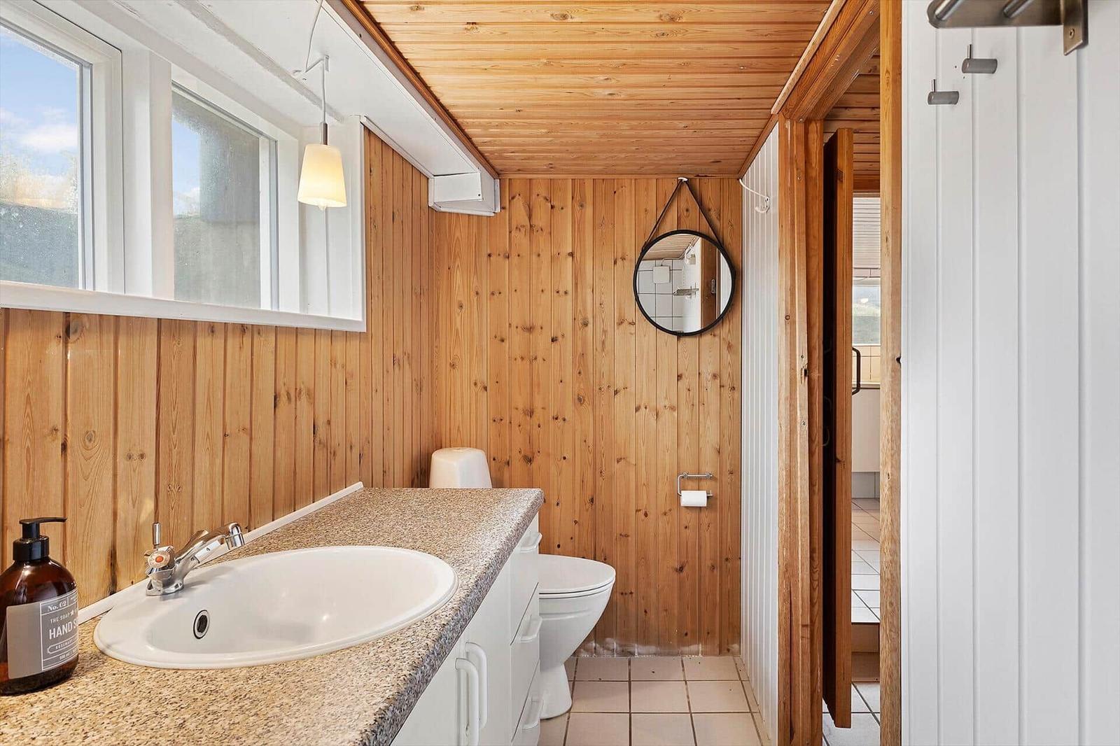 Badezimmer mit Holzwand, Waschbecken und Toilette.