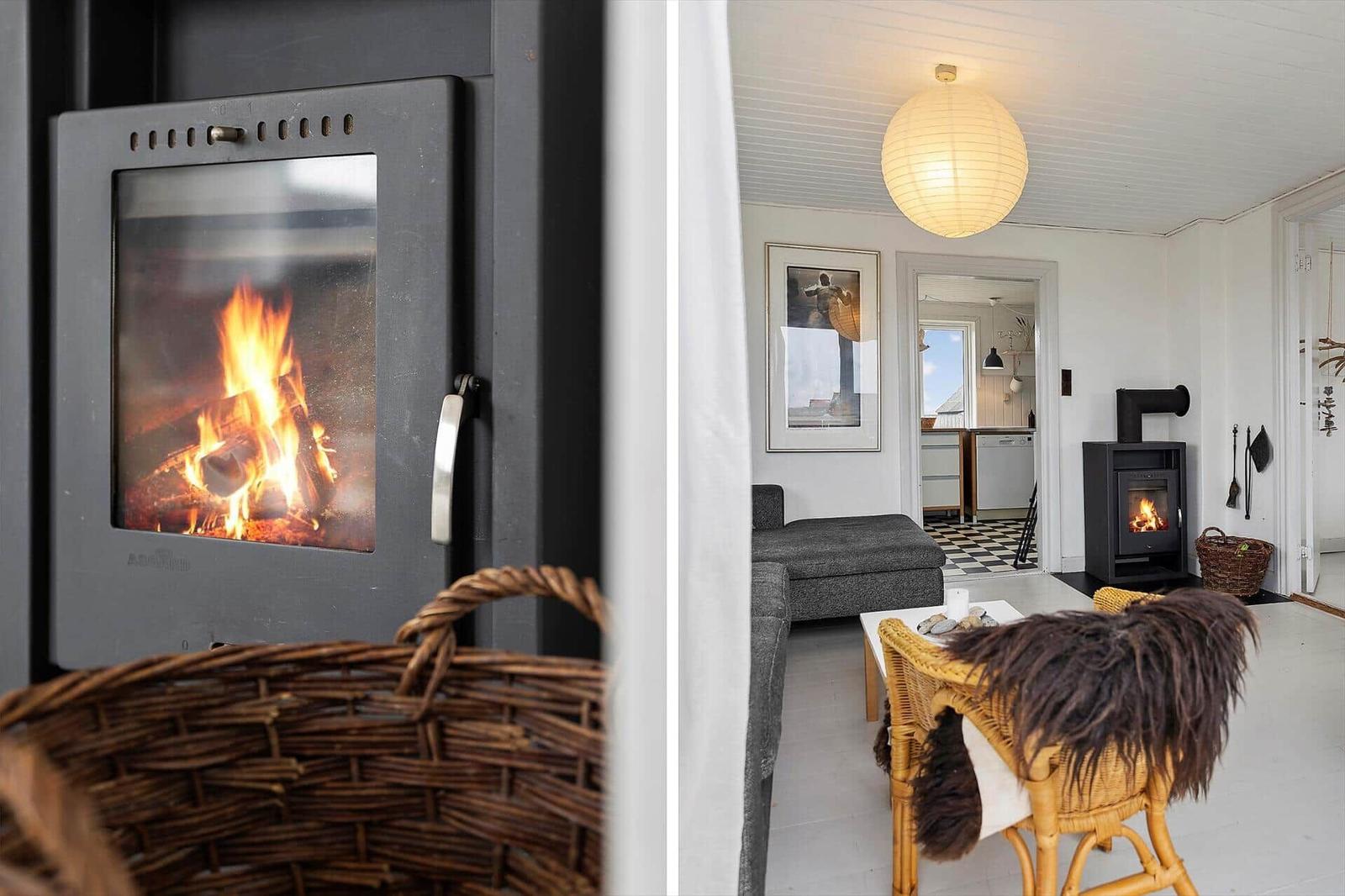 Kaminofen mit brennendem Holz, Wohnzimmer mit Sofa, Stuhl und Pendelleuchte.