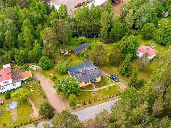 Haus mit Solaranlage in grüner Umgebung mit Wald und Nebengebäuden.