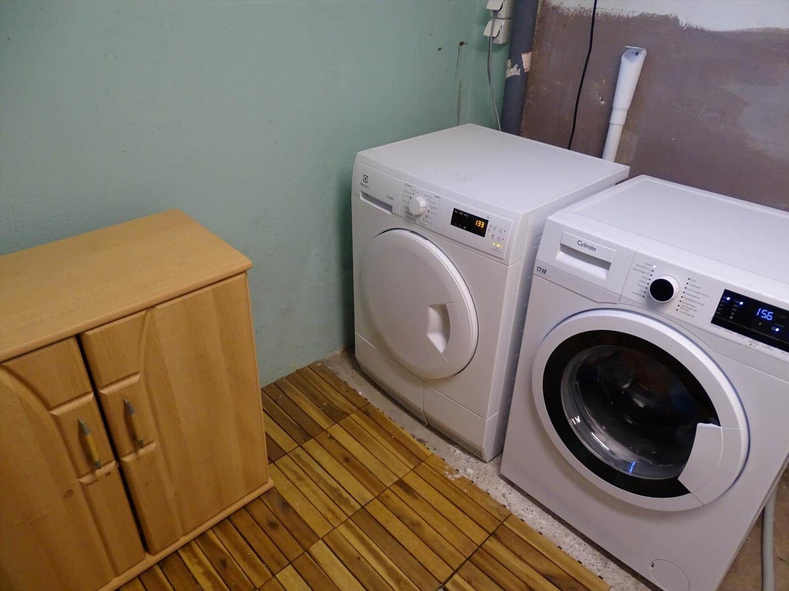Wäschetrockner und Waschmaschine in einem Raum mit Holzboden und Schrank.