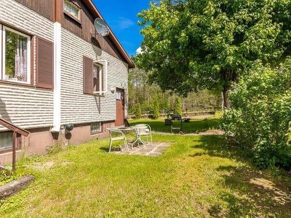 Haus mit Garten, Terrasse und Sitzgelegenheit unter Bäumen.